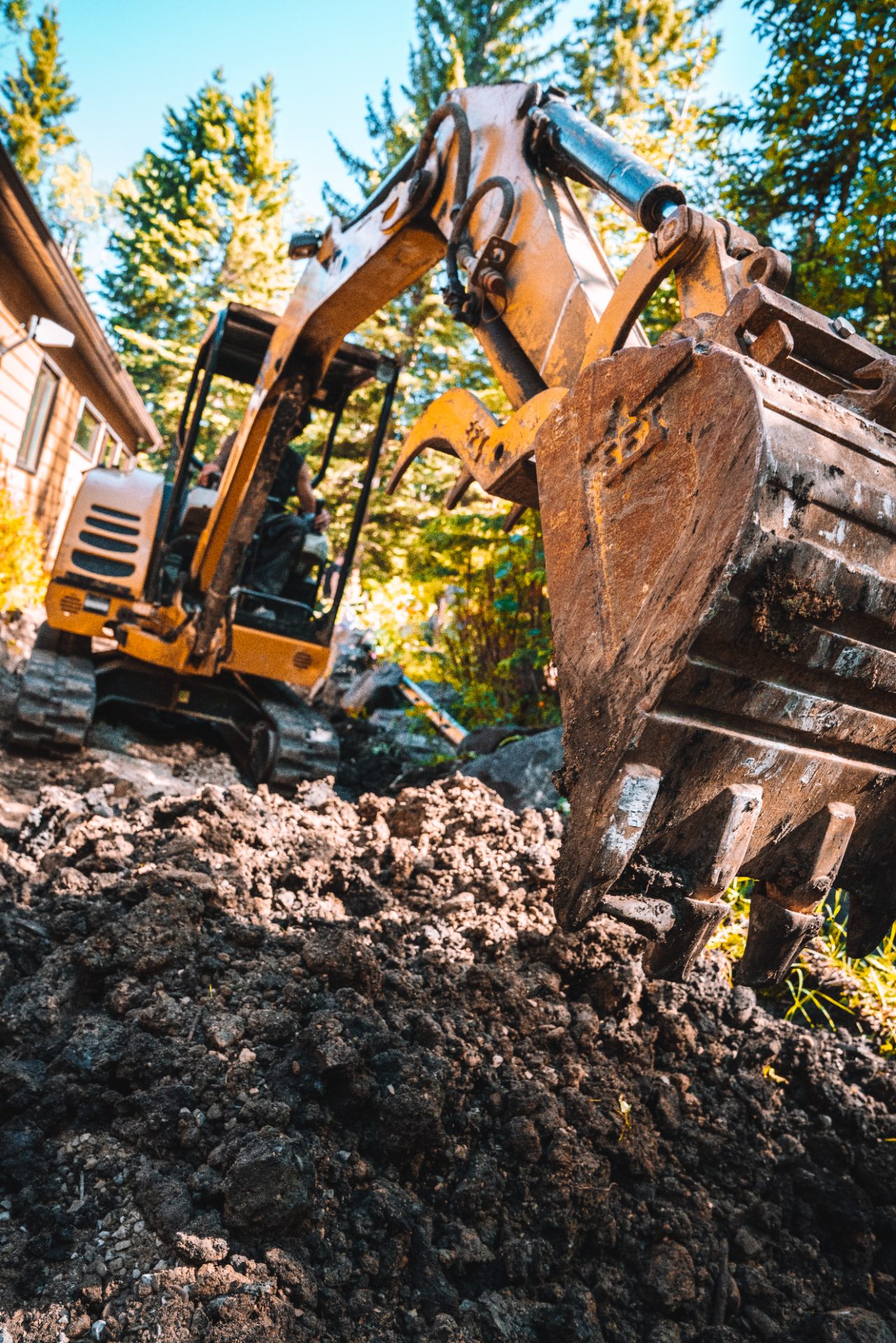 Mini excavator digging tight against a house
