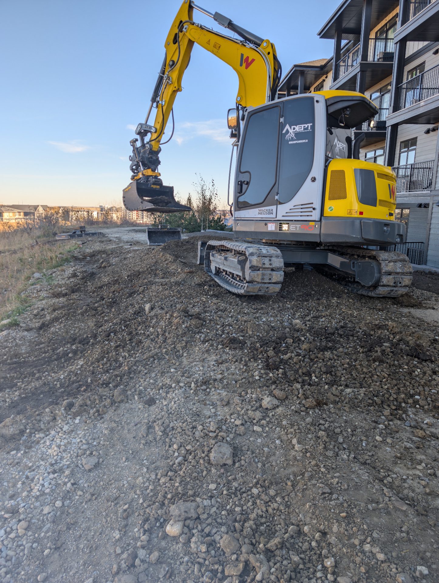 Adept excavator regrading beside a residential building